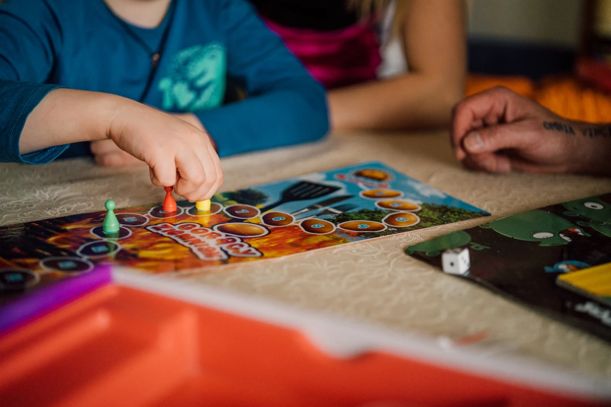 Fotografia przedstawia kadr dłoni dzieci grających w gry planszowe